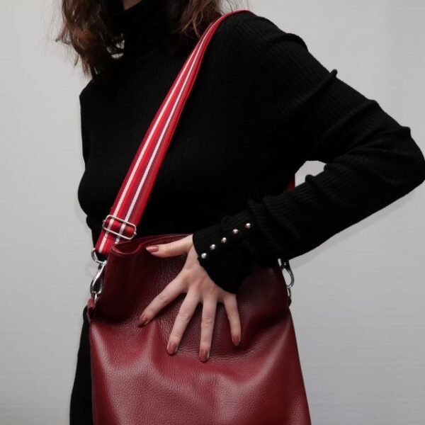 Cette image représente un sac à main en cuir. Il est de couleur rouge avec une anse de 4 centimètres de large de couleur blanche et rouge